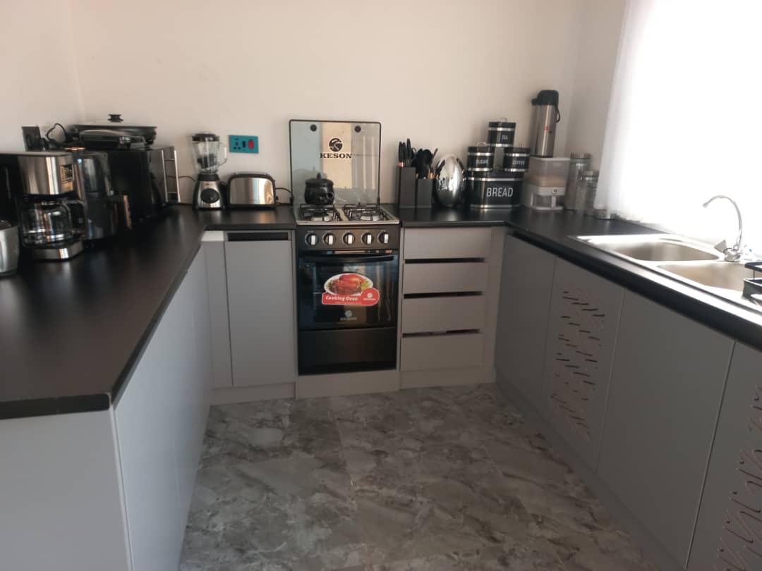 Modern kitchen fit-out with dark countertops, grey cabinetry, and stainless appliances