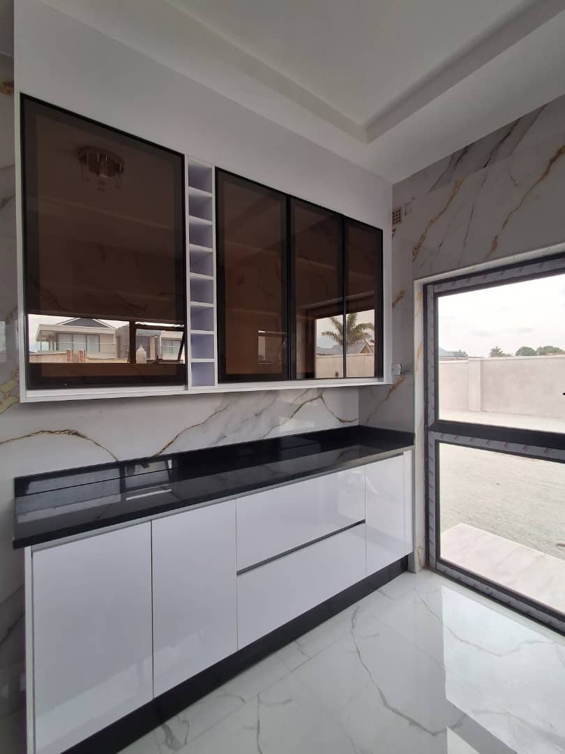 Custom upper kitchen cabinets with smoked glass doors against marble tiled wall