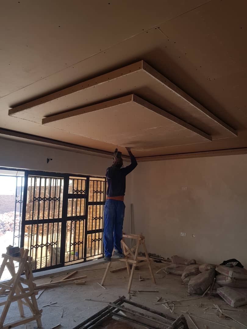 Carpenter installing a layered suspended ceiling with timber framework