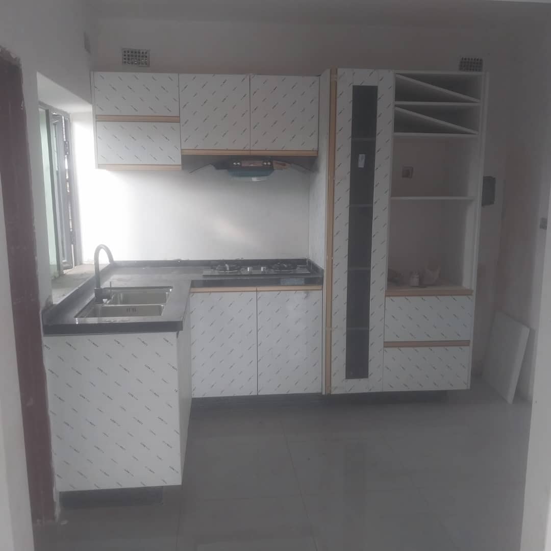 Two carpenters positioning roof truss rafters atop a brick gable wall